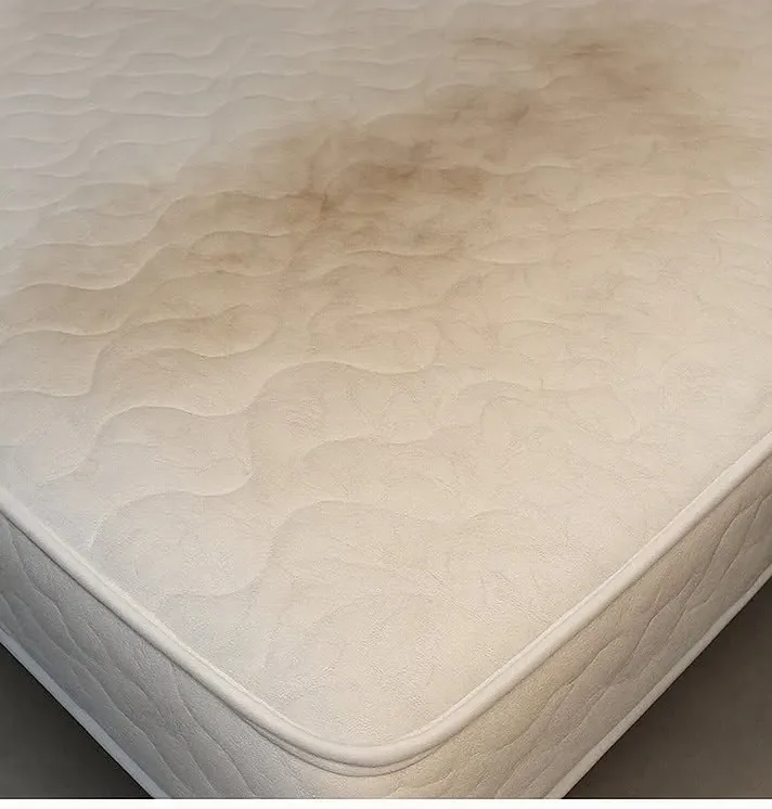 Materasso con un grande alone scuro sulla superficie trapuntata, prima del lavaggio