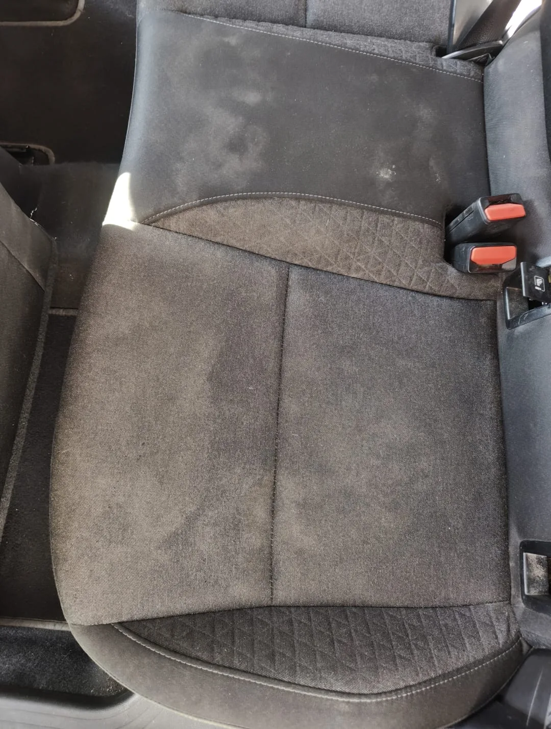 Seduta posteriore di un’auto con macchie e aloni sul tessuto, prima del lavaggio